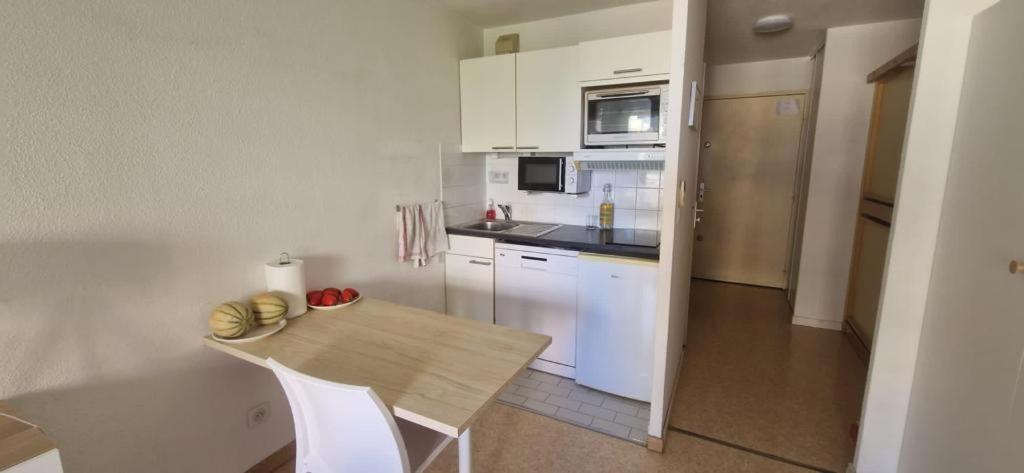 a kitchen with white cabinets and a wooden table at Studio bord de mer à proximité monaco et menton 4 personnes à roquebrune cap martin in Roquebrune-Cap-Martin