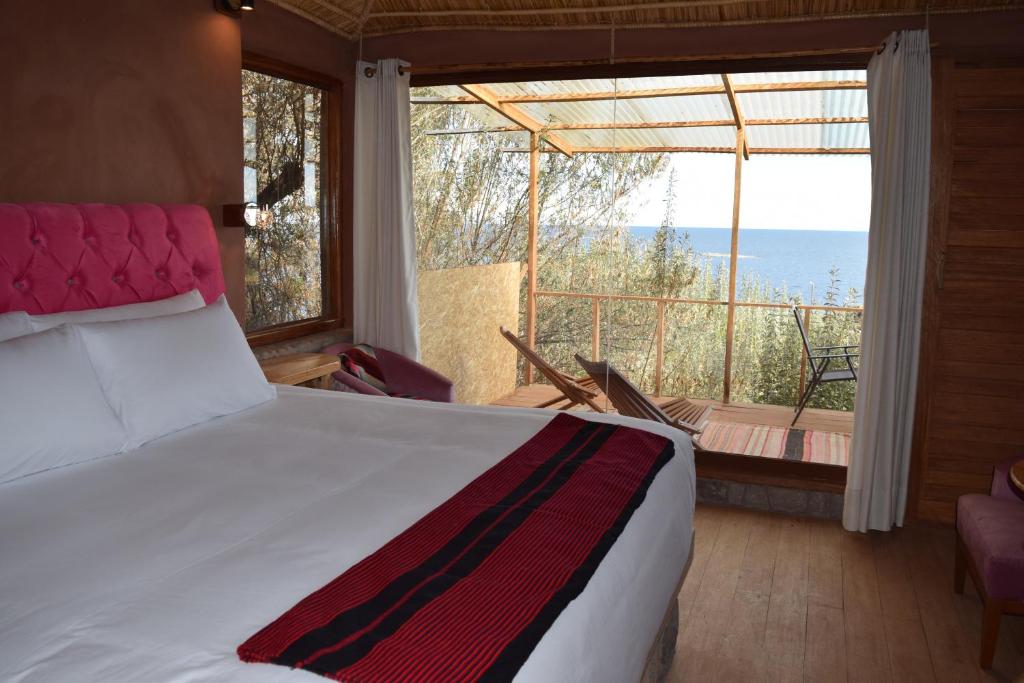 a bedroom with a bed and a view of the ocean at Allpaluxe Peru Lodge in Ocosuyo
