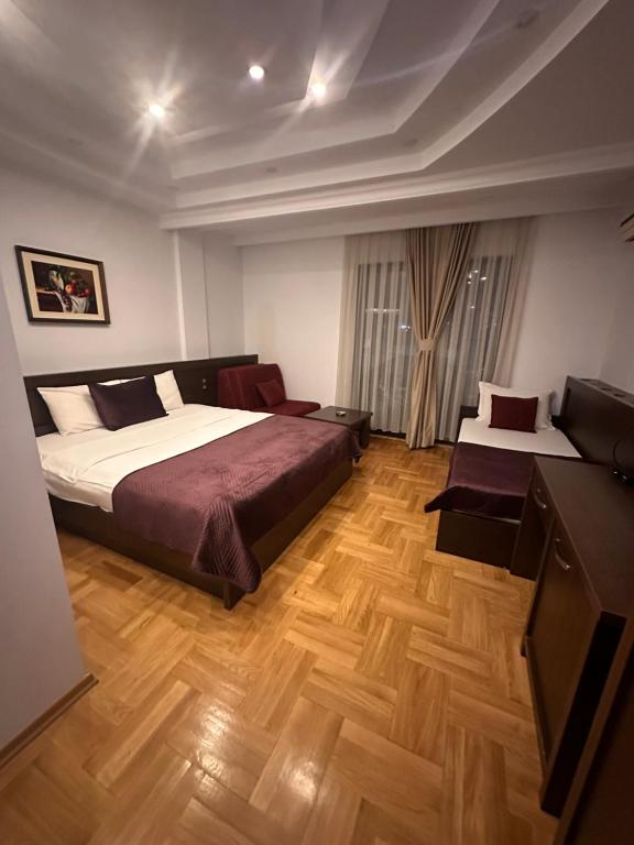 ein Schlafzimmer mit einem großen Bett und einer Kommode in der Unterkunft Hotel Real in Pristina