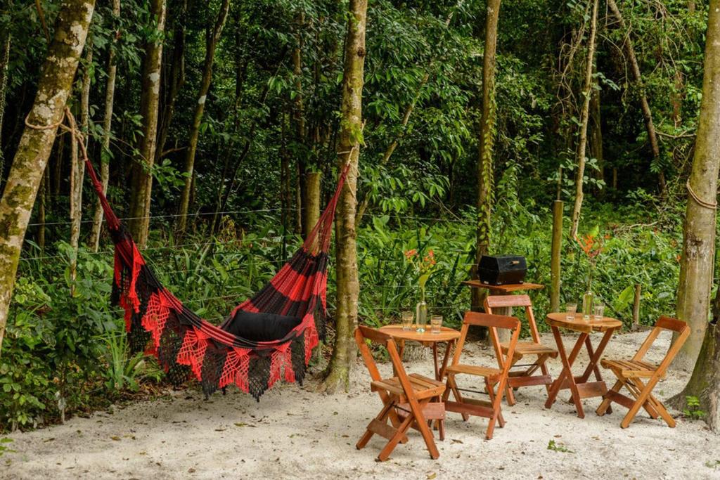 - un hamac avec des tables et des chaises dans une forêt dans l'établissement Chale beira mar c WIFI na Praia do Peixe Grande BA, à Cumuruxatiba