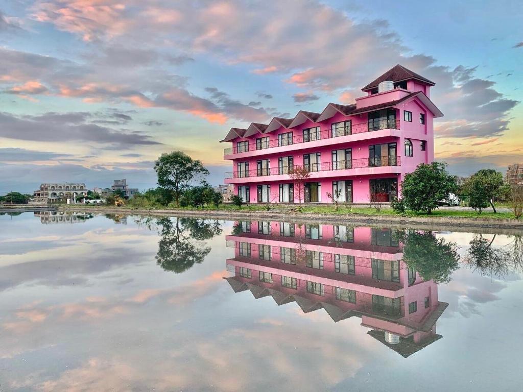 a pink building with its reflection in the water at Pink Castle House in Dongshan