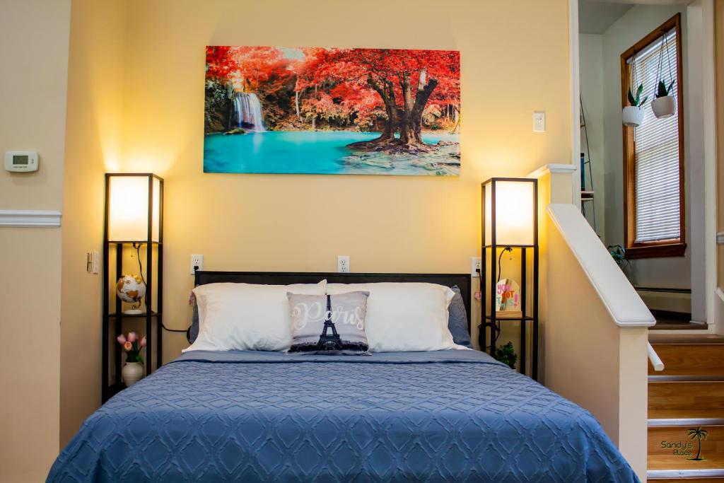 a bedroom with a blue bed and a painting on the wall at Sandy's Place in East Stroudsburg