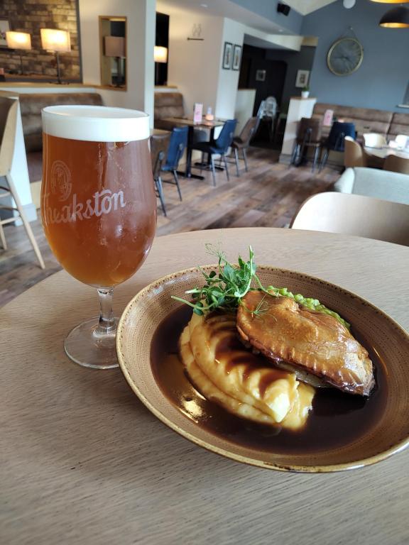 a plate of food and a glass of beer on a table at JJs Lodge Oaktree in Thornton