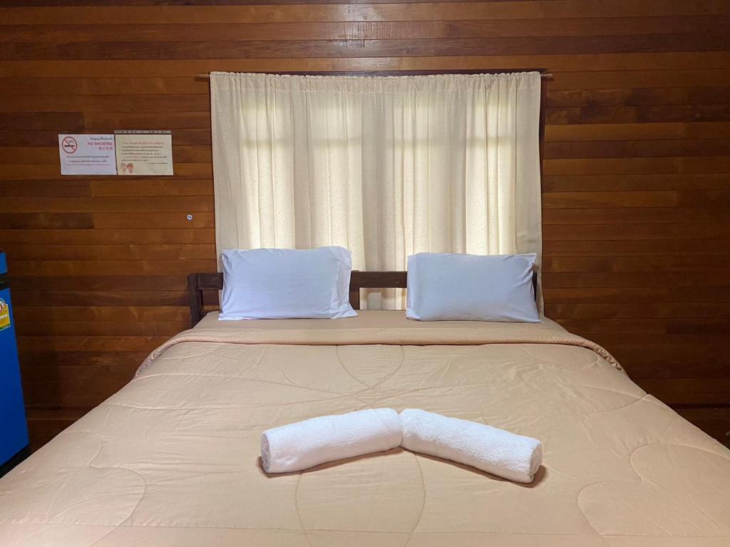 a bed with a towel on it with a window at สวนดวงมณี รีสอร์ท in Ban Tha Thong Mon