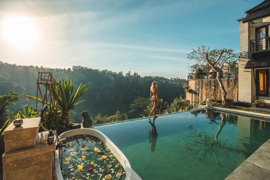 a woman jumping into a swimming pool at a resort at Sunrise Villa in Payangan
