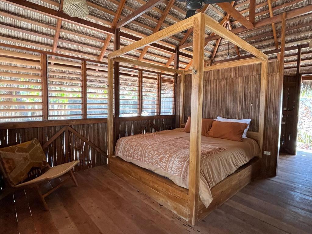 a bedroom with a canopy bed in a wooden house at VILLA LANGIT TEDUH ROTE in Nembrala