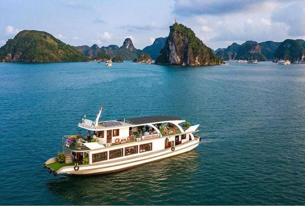 a boat on the water with mountains in the background at New Way Hotel in Cat Ba