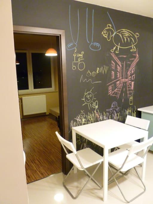 stół i krzesła w pokoju ze ścianą z rysunkami w obiekcie Zachodnia 8th floor apartment w Krakowie