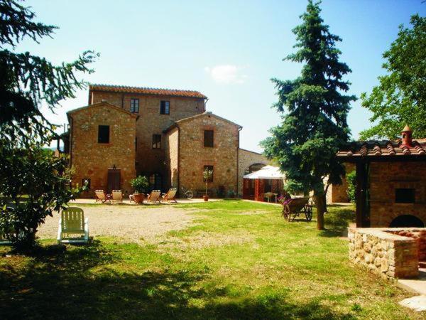 un gran edificio con un patio con sillas y un árbol en Casale Il Colombaio Di Toiano, en Sovicille