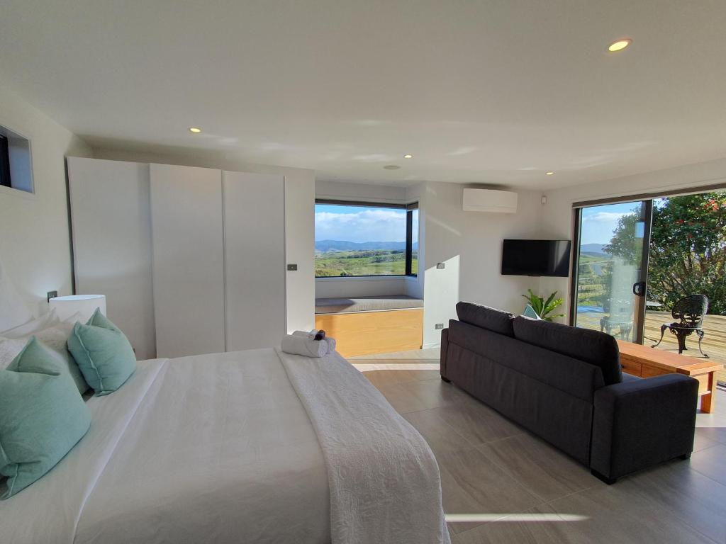 um quarto com uma cama grande e um sofá em Vineyard Vacation em Mangawhai