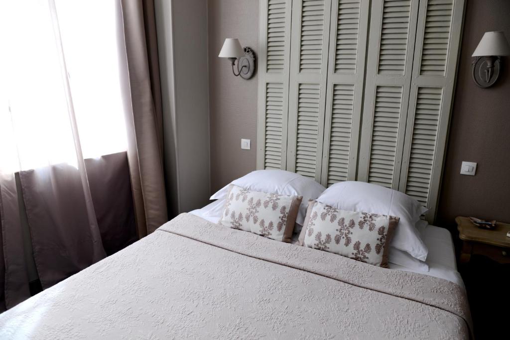 una camera con un letto bianco con due cuscini di La Maison d'Hotes de Saint Leger a Saint-Léger-en-Yvelines
