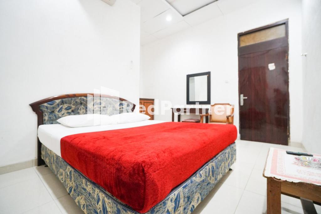 1 dormitorio con 1 cama con manta roja en Hotel Borobudur Kemayoran Syariah Mitra RedDoorz, en Yakarta