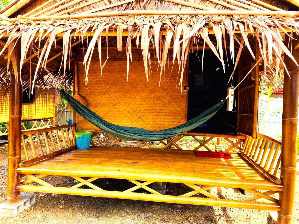a hammock in front of a thatch hut at Asama Bungalow in Ko Lanta