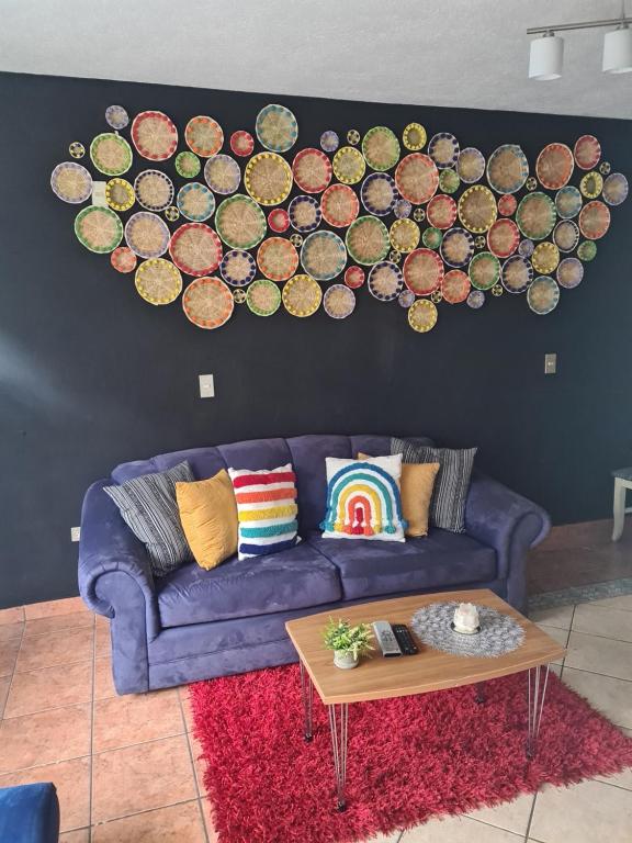 una sala de estar con un sofá púrpura y una pared con una pintura en Apartamento Deluxe Lake Panajachel, en Panajachel