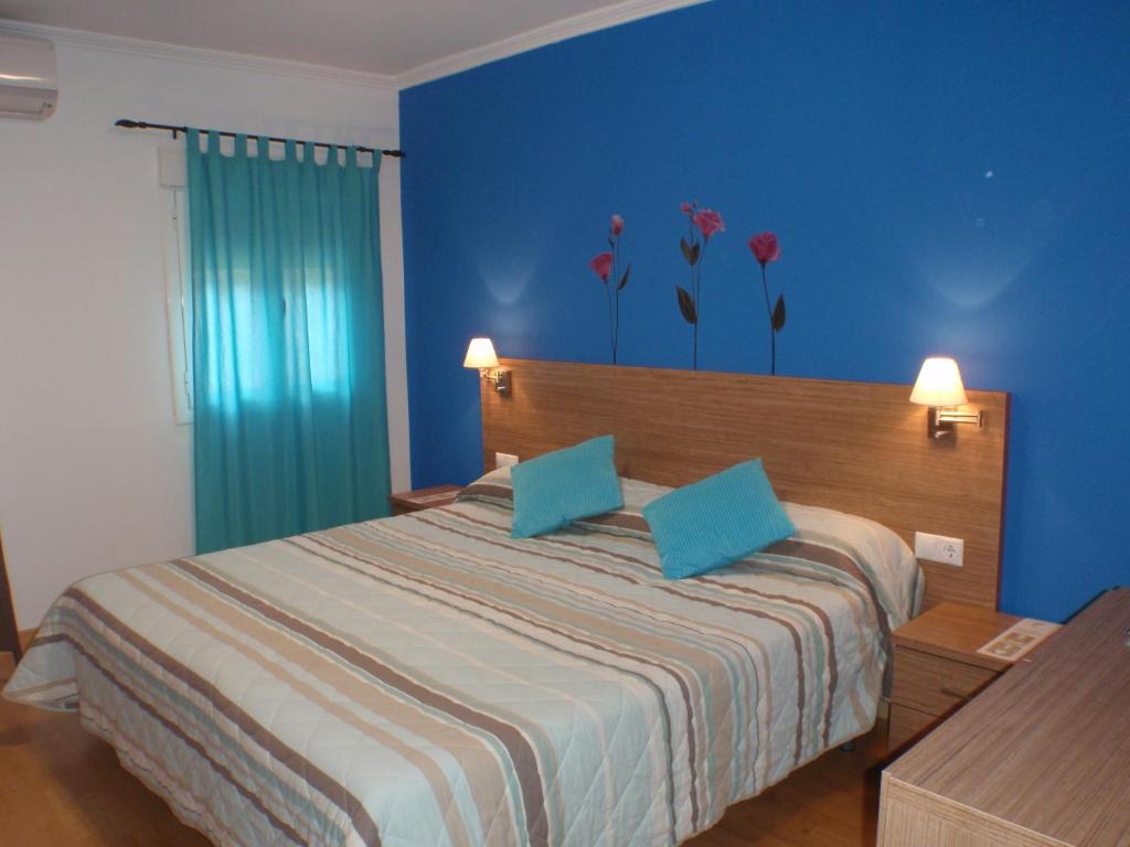 a bedroom with a bed with blue walls and flowers on the wall at El Rento Alojamiento Rural in Cuenca
