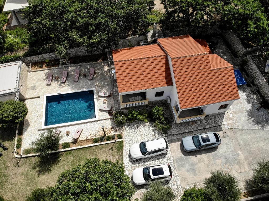 una vista aerea di una casa con auto parcheggiate di fronte di Villa Pag Dubrava Relax with Pool a Pag