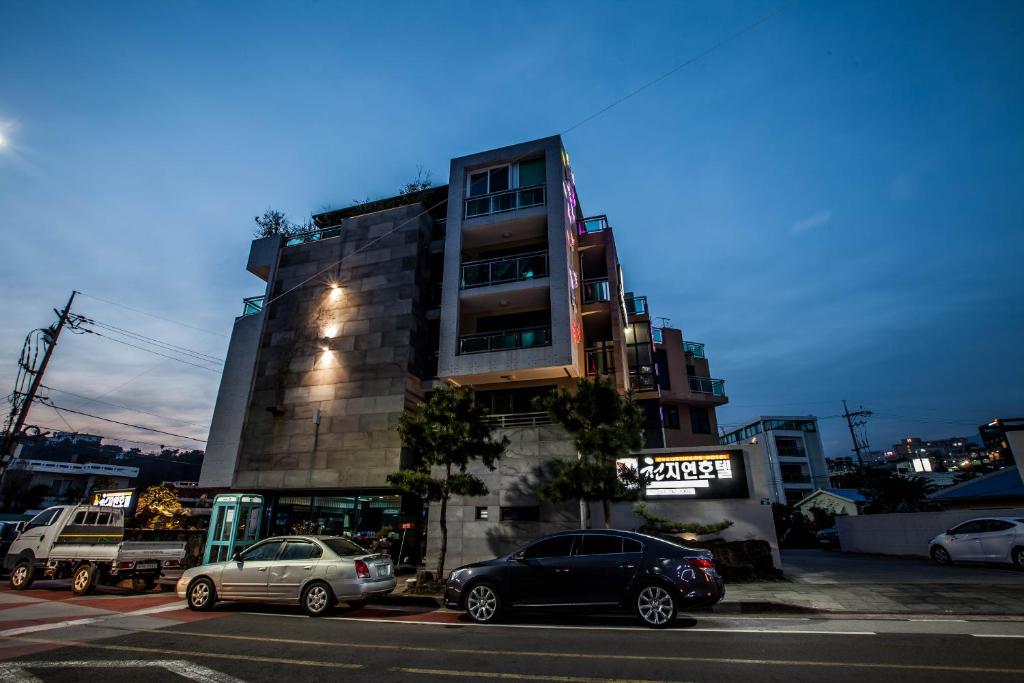 ein hohes Gebäude mit davor geparkt in der Unterkunft Cheonjiyeon Hotel in Seogwipo