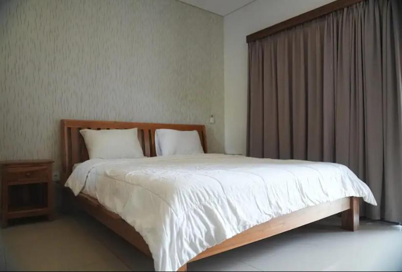 a bedroom with a large white bed and a window at Doris Seminyak Studio in Seminyak