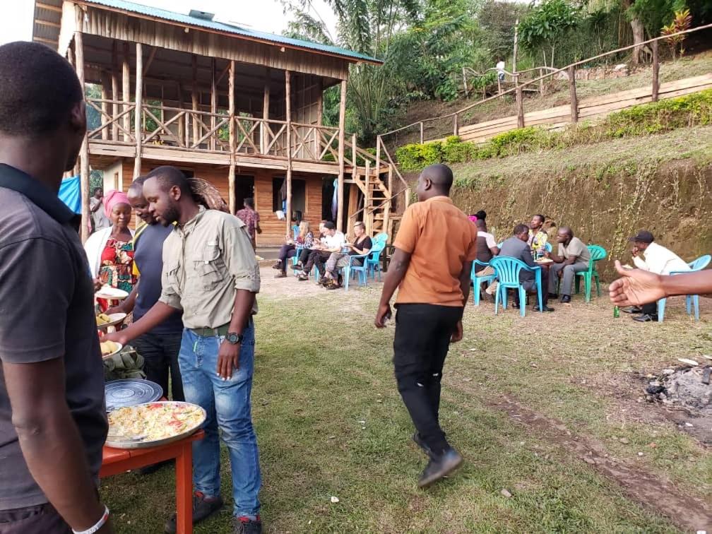 un gruppo di persone che si aggirano intorno a un tavolo con una pizza di Noah's Ark Campsite & Restaurant a Fort Portal