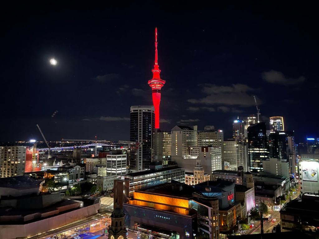 una vista de la ciudad por la noche con una torre roja en Apartment with Brilliant views in Auckland CBD, en Auckland