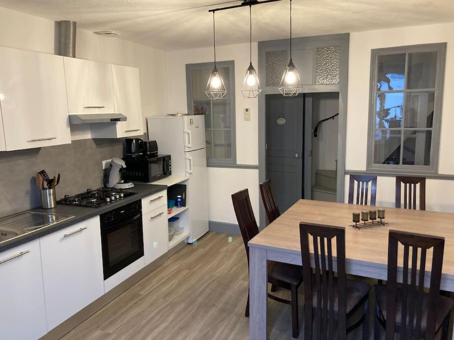 a kitchen with white cabinets and a table with chairs at LA FINNOISE in Fains-les-Sources