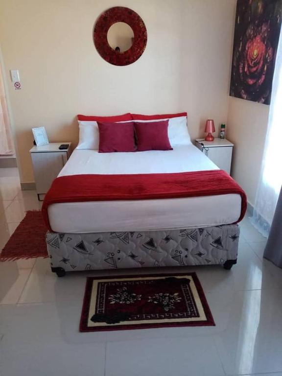 a bedroom with a large bed with red pillows at Ngwane Park Guest House in Manzini