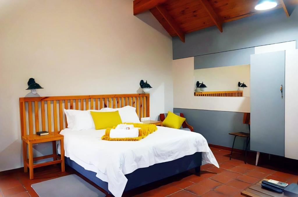 1 dormitorio con 1 cama blanca grande con almohadas amarillas en De Werf Lodge, en Keimoes