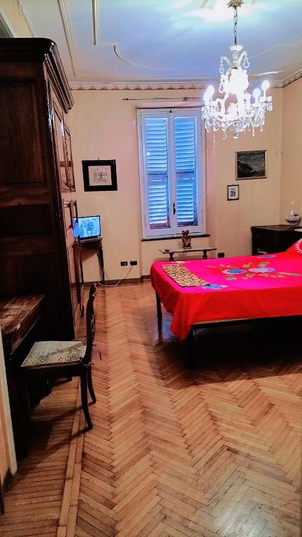 Schlafzimmer mit einem roten Bett und einem Kronleuchter in der Unterkunft Nevina centro camera privata in appartamento in Parma