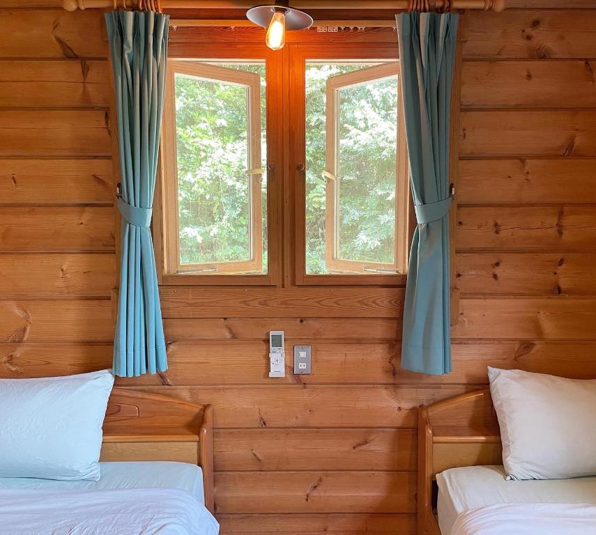 2 camas en una habitación con 2 ventanas en Sunny Side Cottage en Shimoda
