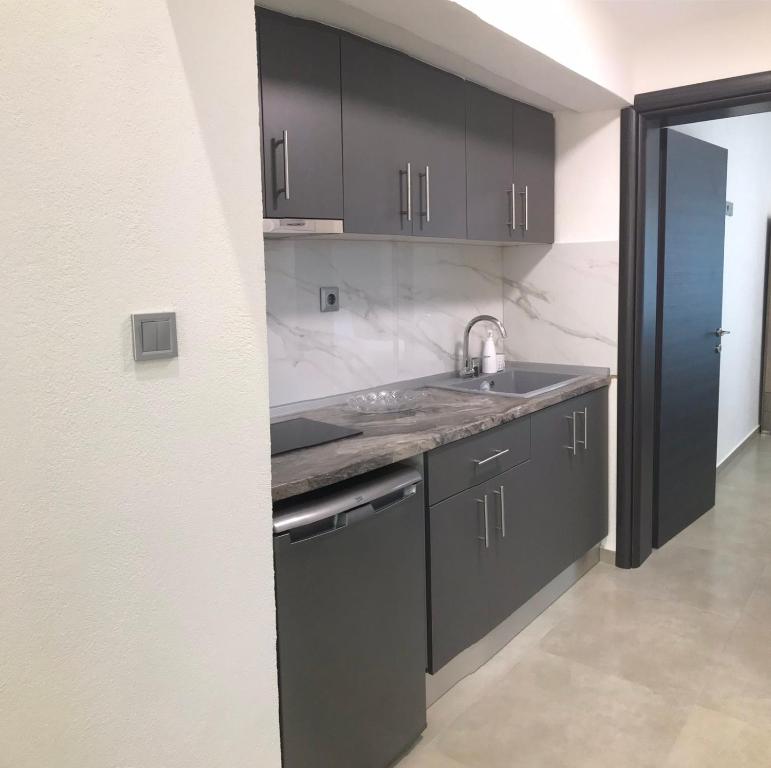a kitchen with black cabinets and a sink at My House Apartments in Pyrgadikia