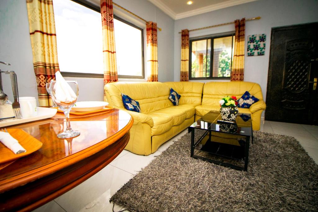 a living room with a yellow couch and a table at Indigo cottage and Apartment in Kumasi