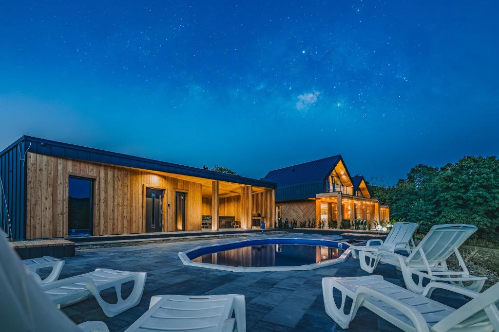 a house with a pool and lounge chairs at night at Słone Wzgórze in Rabka-Zdrój
