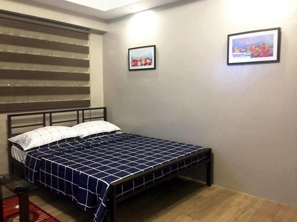 1 dormitorio con 1 cama con manta de cuadros azul en Monte Carlo Residenze, en Manila