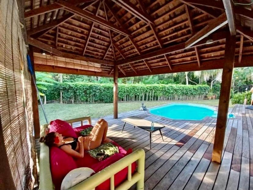 uma mulher deitada num sofá debaixo de um pavilhão ao lado de uma piscina em Moorea Temae Villa walking dist beach and golf em Moorea