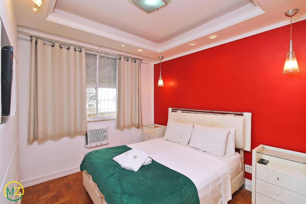 a bedroom with a red wall and a white bed at Apartamento econômico e espaçoso para 6 pessoas in Rio de Janeiro