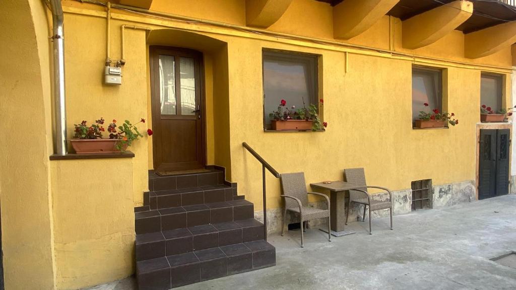 een geel gebouw met een tafel, stoelen en ramen bij Bretsara in Bistriţa