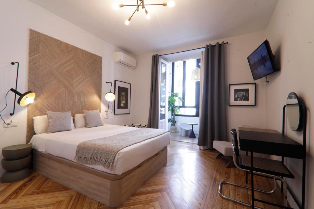1 dormitorio con cama, escritorio y ventana en Suites You Gran Vía, en Madrid