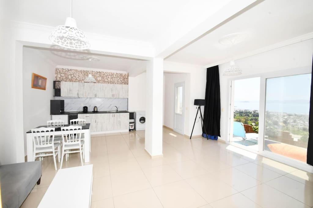 een witte keuken en een woonkamer met een tafel en stoelen bij Wohnung mit Meerblick in Bodrum City