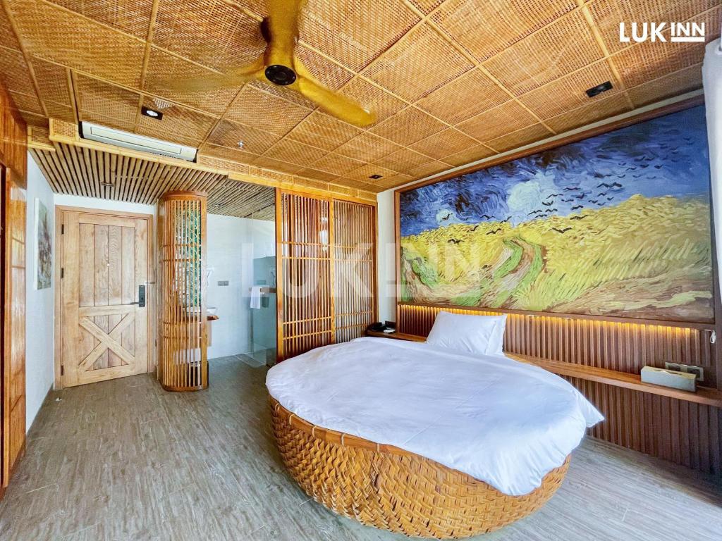 a bedroom with a large bed with a painting on the wall at LUK Inn Hotel in Da Nang