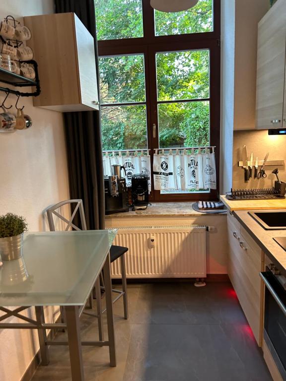 eine Küche mit einem Tisch und einem großen Fenster in der Unterkunft Ruhige Wohnung im Fabrikstil in Chemnitz in Chemnitz