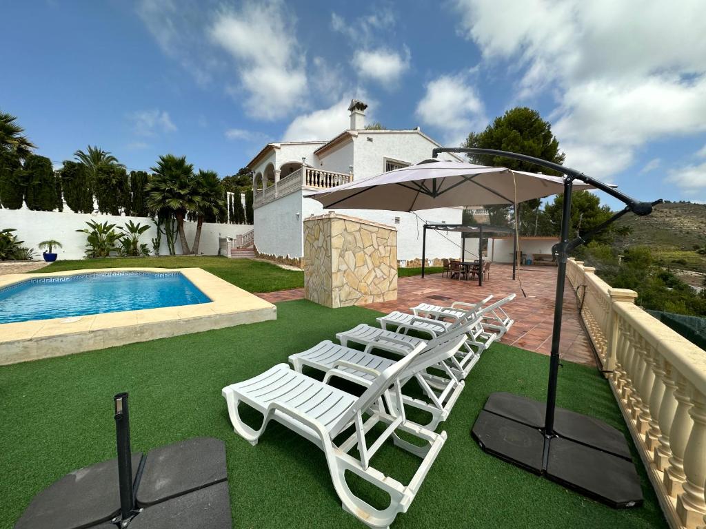 a group of lounge chairs and an umbrella next to a pool at Villa Maja in Calpe