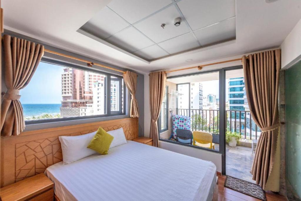 ダナンにあるTaian Hotel & Apartmentのベッドルーム1室(海の景色を望む大きな窓付)