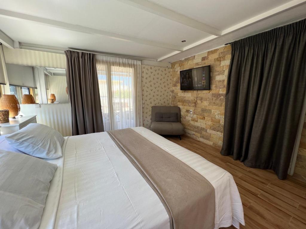 ein Schlafzimmer mit einem großen weißen Bett und einem Stuhl in der Unterkunft Reginas Apartments in Ixia