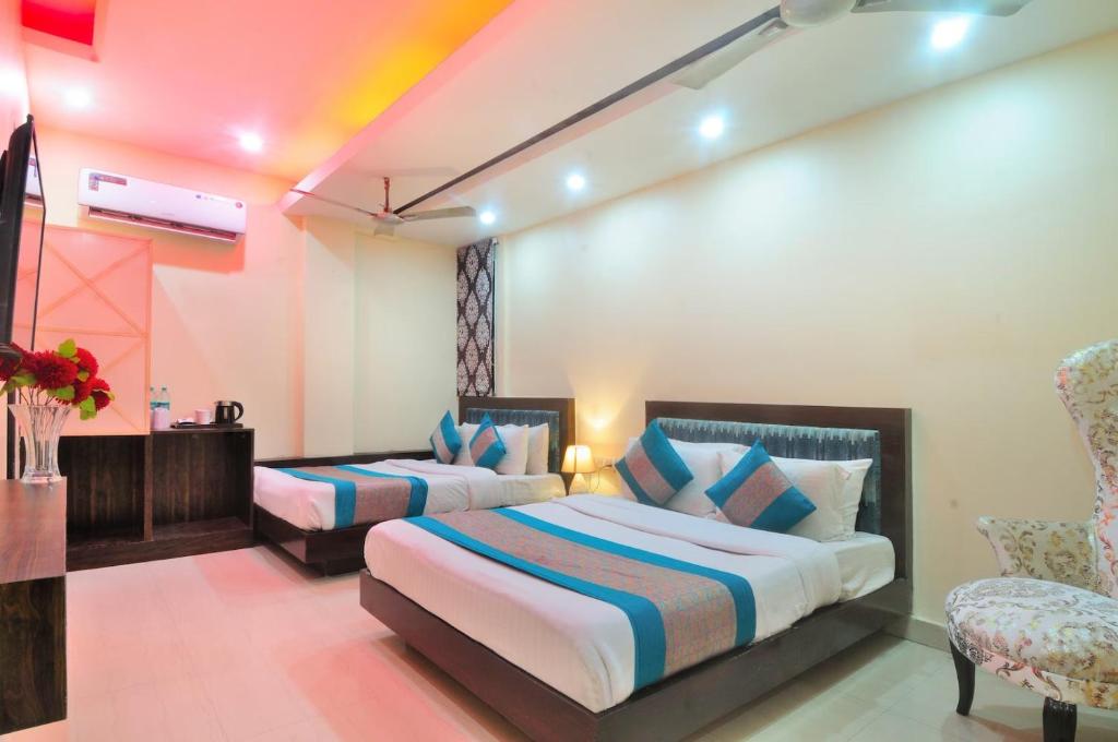 um quarto de hotel com duas camas e uma cadeira em Staybook Hotel Aira, Paharganj, New Delhi Railway Station em Nova Deli