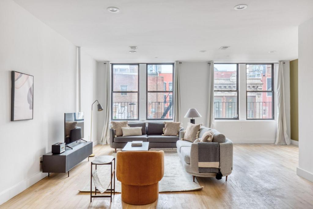 a living room with a couch and chairs and windows at Soho 3br w wd elevator nr cafes restaurants NYC-1043 in New York