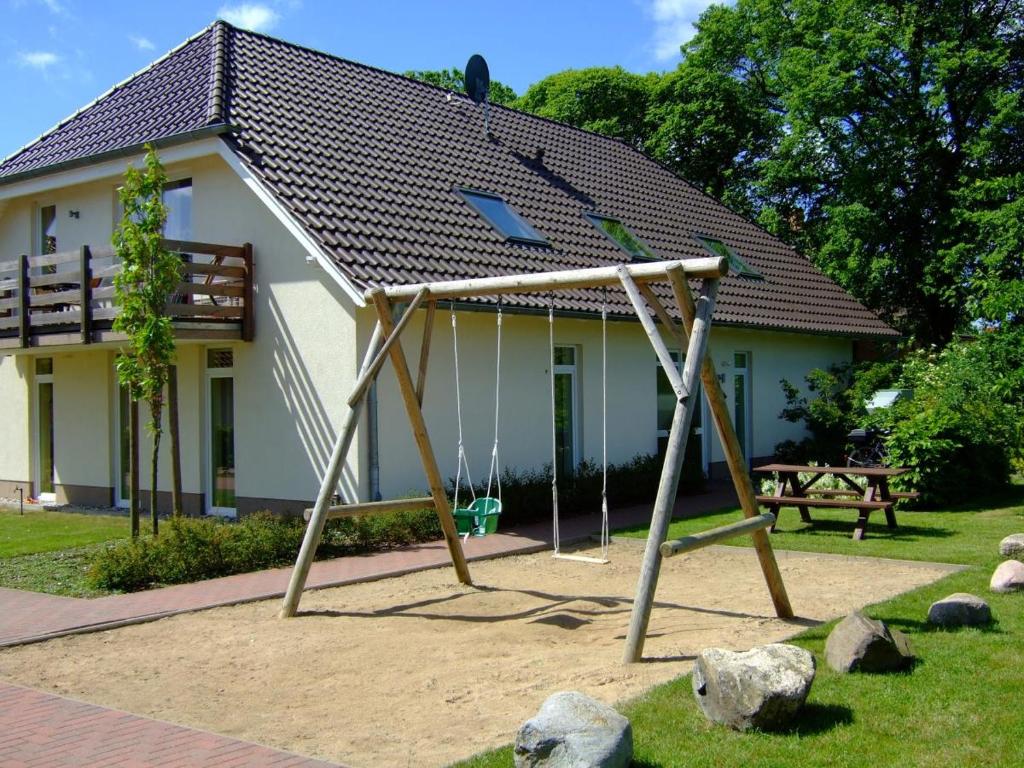 a swing set in front of a house at 4 Sterne Apartment Hühnergott mit Terrasse und Sauna in Lobbe