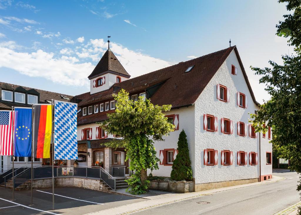 een groot wit gebouw met vlaggen ervoor bij Wirtshaus & Hotel Goldener Greif in Edelsfeld