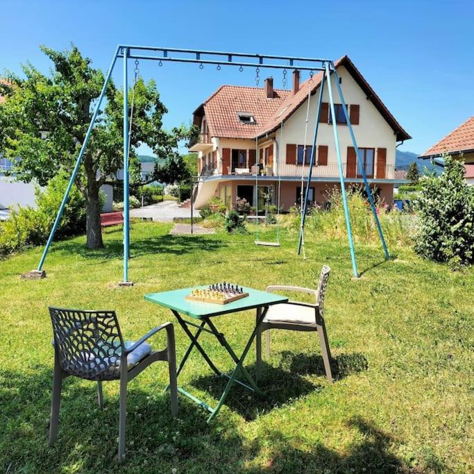 - une table, deux chaises et une balançoire dans la cour dans l'établissement Au Piémont des Vosges, à Gertwiller