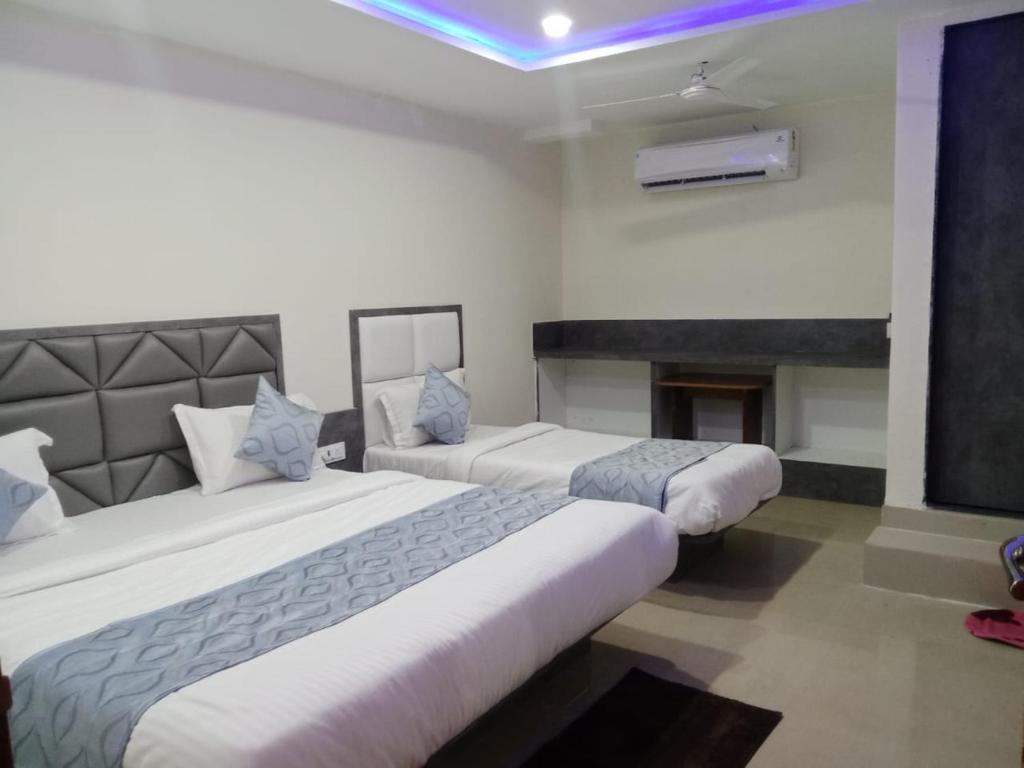 2 Betten in einem Hotelzimmer mit Kamin in der Unterkunft HOTEL RK VILLA in Vadodara
