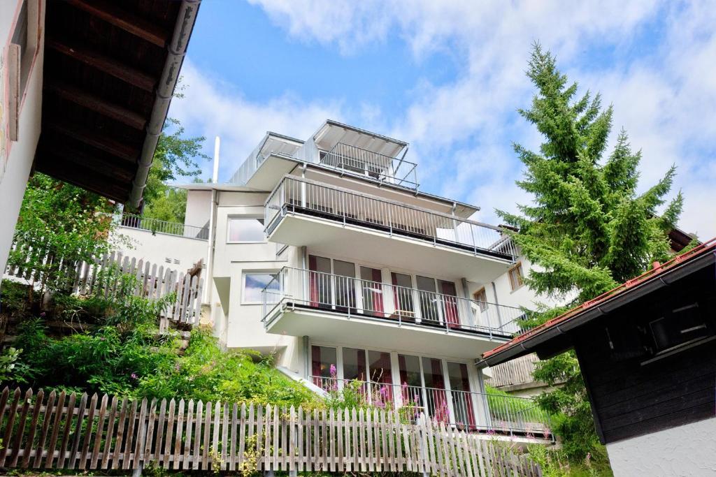 Ein weißes Gebäude mit einem Zaun davor. in der Unterkunft Villa Chiara in Sankt Anton am Arlberg